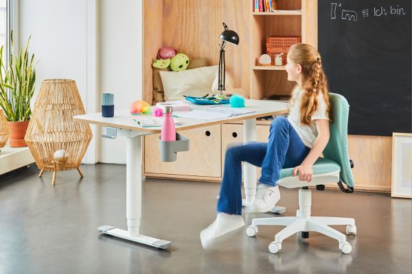 Empfehlenswerte Einrichtung fürs Kinderzimmer Mädchen sitzt am Schreibtisch. Linkt zu Kindermöbel.